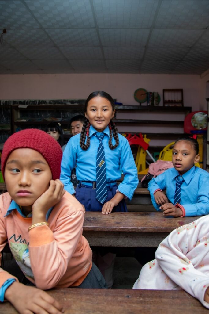 Children in a classroom wearing school uniforms.